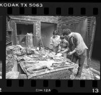 Joaquin Coronel, Luis Flores and Juan Villa sorting belongs in burned out apartment in Los Angeles, Calif., 1986