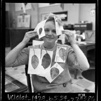 Los Angeles City Hall employee displaying leaves sent to City Hall in "Leaves for Parks" campaign, 1965