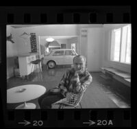 Emil Seliga sitting in the rumpus room of his Los Angeles, Calif. home along with the family's British MG automobile, 1964