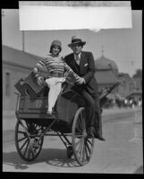 Gus Edwards and Senorita Armida atop a luggage cart, 1928