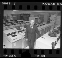 William R. Hoover, president of Computer Sciences Corp. standing amongst rows of computer data banks, Calif., 1977