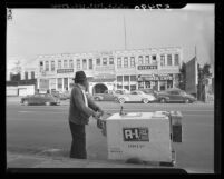Street vendor gazing at old structure which will be torn down to make way for Hollywood Freeway, Los Angeles, 1949