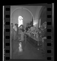 Mourners kneeling at the casket of Ruben Salazar at his funeral, Newport Beach, 1970