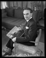 Architect Richard J. Neutra holding photograph of Beard House and pipe, Los Angeles, 1935