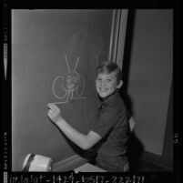 Child actor Kurt Russell drawing on a blackboard while waiting for judge to approve television contract in Los Angeles, Calif., 1963