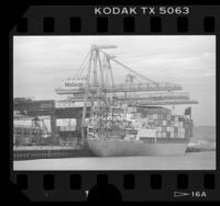 Cranes loading freight containers onto the cargo ship Kauai in the Port of Los Angeles, Calif., 1986