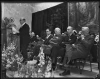 Gordon L. McDonough, Harry M. Baine, Earl E. Jensen, and Hugh A. Thatcher observe from their seats as Dr. Percy T. Magan speaks at the podium, Los Angeles, 1934