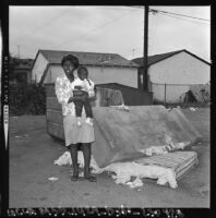 Woman and baby on sidewalk in Watts, Los Angeles (Calif.)