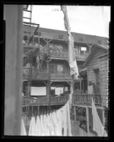 Housing Director Holtzendorff and men going up rickety fire escape of tenement during tour of slum areas in Los Angeles, Calif., 1948
