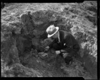 Man inspecting cracker box in hole, ransom drop-off point in Mary B. Skeele kidnap case, Los Angeles, 1933