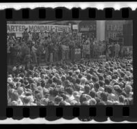 Presidential candidate Jimmy Carter on platform with politicians, actors and activists behind him during campaign stop in Los Angeles, Calif., 1976