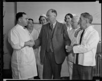 Dr. Edgar Spear and nurse Charles Whitehead shake hands with Police Detective Vern Filby at the Georgia Street Hospital, Los Angeles, 1936