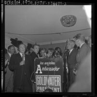 Barry Goldwater standing at podium surrounded by press and supporters during election returns in 1964 California primary