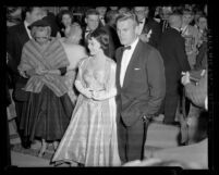 Actors Natalie Wood and Tab Hunter arriving at the 28th Academy Awards with gossip writer Louella Parsons in background, 1956