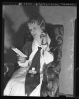 Aimee Semple McPherson seated, reading note demanding $10,000, 1936
