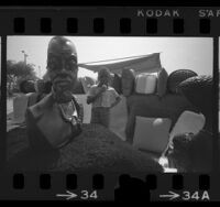 Young boy peering at sculptures during the fifth annual Watts Summer festival, 1970