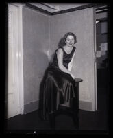 Film actress Melody Riley sits on a table in a formal dress, Los Angeles, 1931