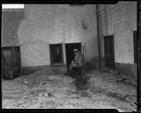 A man with a shovel clearing a path through mud to a doorway after a catastrophic mudslide, La Crescenta-Montrose, 1934