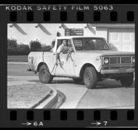 City worker cruising in truck spraying gutter with pesticides to control mosquitoes in South Gate, Calif., 1984