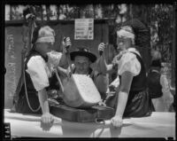 Bertha Reinharth and Alma Dube cut cheese while wearing blindfolds as Hans Leiss observes, Los Angeles, 1935