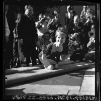 Actress Debbie Reynolds smiling and displaying cement-covered hands after making imprint at Grauman's Chinese Theater, Hollywood (Los Angeles), 1965