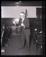 Attorney William E. Simpson standing alone in courtroom clenching both fists, Los Angeles, circa 1931