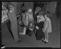 Santa Claus offers a doll to young girls, Los Angeles, 1935