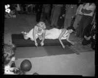 Actresses Marilyn Monroe and Jane Russell putting signatures, hand and foot prints in cement at Grauman's Theater, 1953