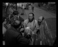 Bishop Asaiah talks with police and reporters outside the ruins of the headquarters of the Fountain of the World religious collective. B. 1958