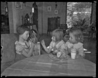 Three unidentified girls feed a dog an avocado, Los Angeles County, 1935