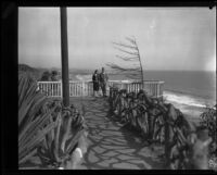 Woman and man standing near metal fence, Palisades Park, Santa Monica, [1930s?]