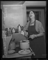 Singer Mariska Aldrich prepares food over a stove, Los Angeles, 1935