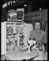 Woman demonstrates electric can opener at National Housing Exposition, Los Angeles, 1935