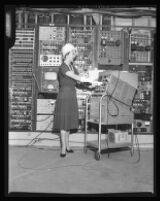 Woman standing in front of a wall of installed electronic equipment, Los Angeles, 1960