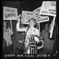 Barbra Streisand surrounded by "Clear Day" film crew holding signs congratulating her on winning Oscar for "Funny Girl," 1969