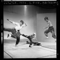 Four men performing karate before backdrops with images of Bruce Lee during audition for movie in Los Angeles, Calif., 1975