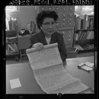 Mrs. Man Hing Mok, head of UCLA Oriental Library holding ancient Tibetan manuscript-scroll, 1964