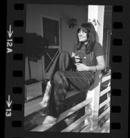 Singer Linda Ronstadt reclining on porch railing in Los Angeles, Calif., 1974