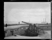 One of the 14-inch caliber guns at Fort MacArthur with the parade of the navy fleet in the background, San Pedro, 1932