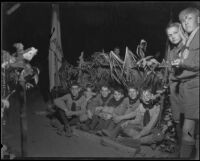 Boy Scouts seated in front of a lean-to shelter at a camping event, circa 1935