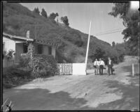 Three men passing a gate house and road gate at Will Rogers' ranch, Pacific Palisades, 1935