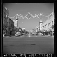 Street scene of 3rd Street with holiday ornaments strung across street in Santa Monica, Calif., 1963