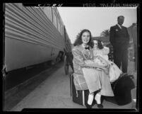 11 year-old actress Margaret O'Brien seated on suitcase holding a doll at Los Angeles Union Station, 1948