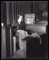 Eunice Pringle on the witness stand examining a dress during Alexander Pantages rape trial, Los Angeles, 1931