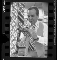 Rudy Cervantes inspecting Mickey Mouse ties in Los Angeles, Calif., 1976