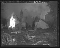 Two firemen standing in remains of house destroyed by Howard Hughes' FX-11 plane crash in Los Angeles, Calif., 1946