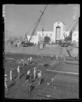 Cranes swing large cement buckets of concrete to foundation floor of city hall in Burbank, Calif., 1960