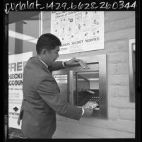 Mas Miyakoda, manager of Sumitomo Bank of California demonstrating how to use ATM machine in Monterey Park, Calif., 1969