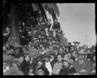 Spectators with three boys perched on a tall sign at the Tournament of Roses Parade, Pasadena, 1932