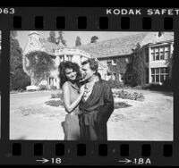 Publisher Hugh Hefner in trademark pajamas with Carrie Leigh in front of Playboy Mansion in Los Angeles, Calif., 1984